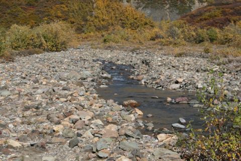 1990 Chevrolet Suburban - A natural landscape scene a creek flowing through a rocky terrain with hills displaying autumn colors.