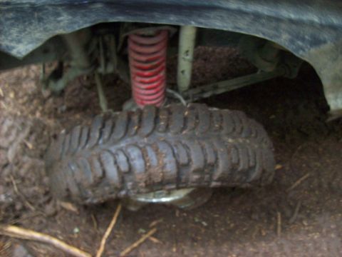 1985 Toyota Pickup/SR5 - Close-up of a muddy off-road tire and suspension system, likely from a truck or SUV.