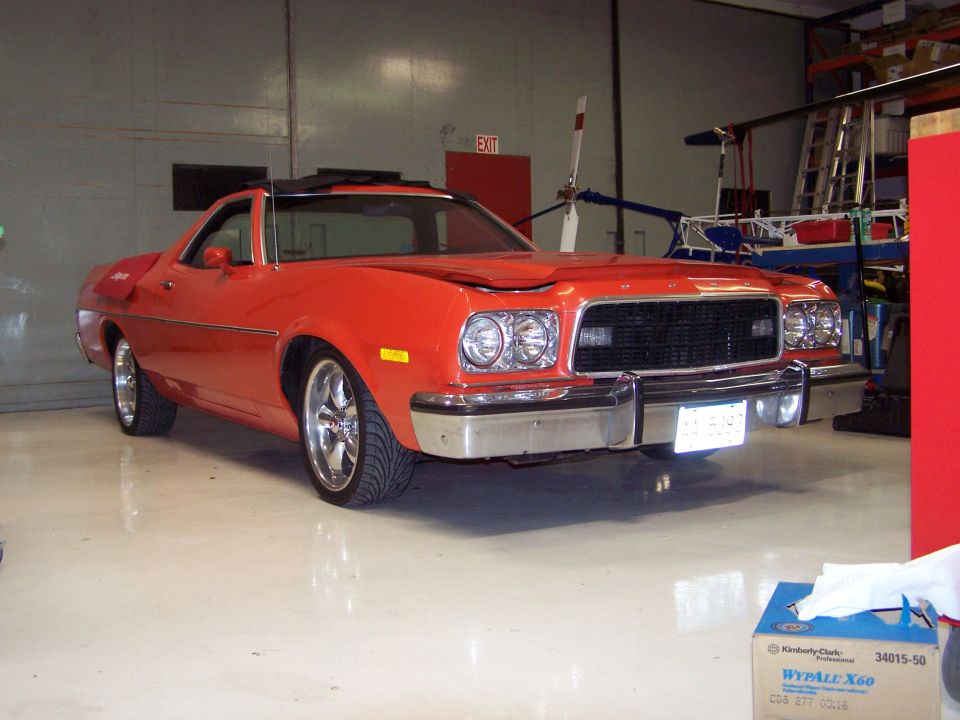 Orange 1973 Ford Ranchero parked indoors with aftermarket wheels