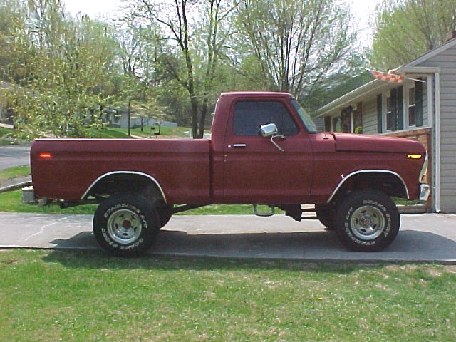 Maroon lifted Ford pickup, side view, on chrome wheels parked in driveway
