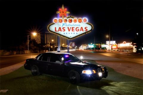 1900 Bentley Turbo - A black police car is parked in front of the iconic 'Welcome to Fabulous Las Vegas' sign at night.