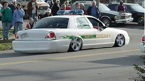 1900 Bentley Turbo - A modified sheriff's car with a lowered stance and custom wheels is seen with onlookers in the background.