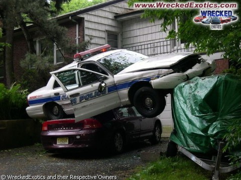 1900 Bentley Turbo - A police car has crashed and ended up on top of another vehicle, creating a precarious scene.