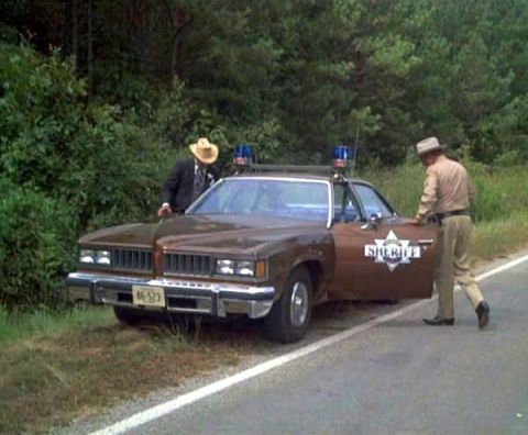 1900 Bentley Turbo - A sheriff's car is parked on the side of a road with two men standing near it.