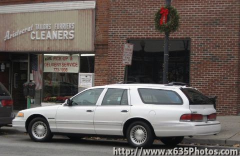 1900 Bentley Turbo - A white station wagon is parked on the street in front of a brick building with a "Cleaners" sign.