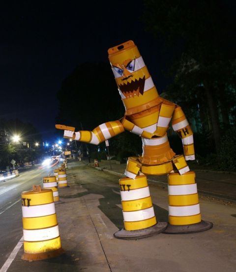 1900 Bentley Turbo - A creative traffic cone sculpture resembling a robot stands guard on a city street after dark.