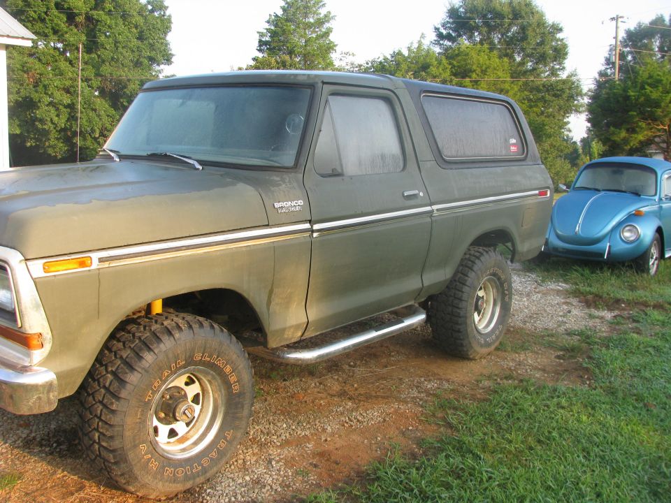 Green 1978 Ford Bronco parked next to a blue Volkswagen Beetle