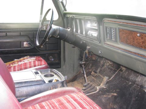 1979 Ford Bronco - The interior of a 1979 Ford Bronco, a dashboard with wood grain accents, a column shifter, and striped upholstery.