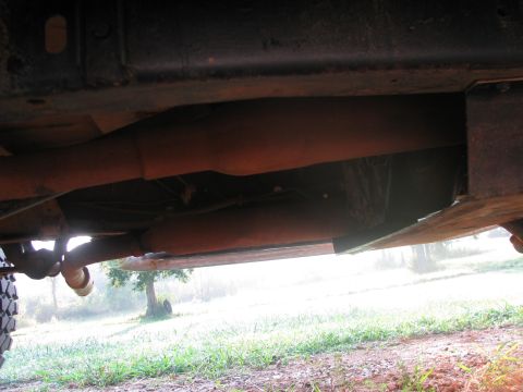 1979 Ford Bronco - Underside view of vehicle frame and exhaust system. Tire tread is visible on the left side.