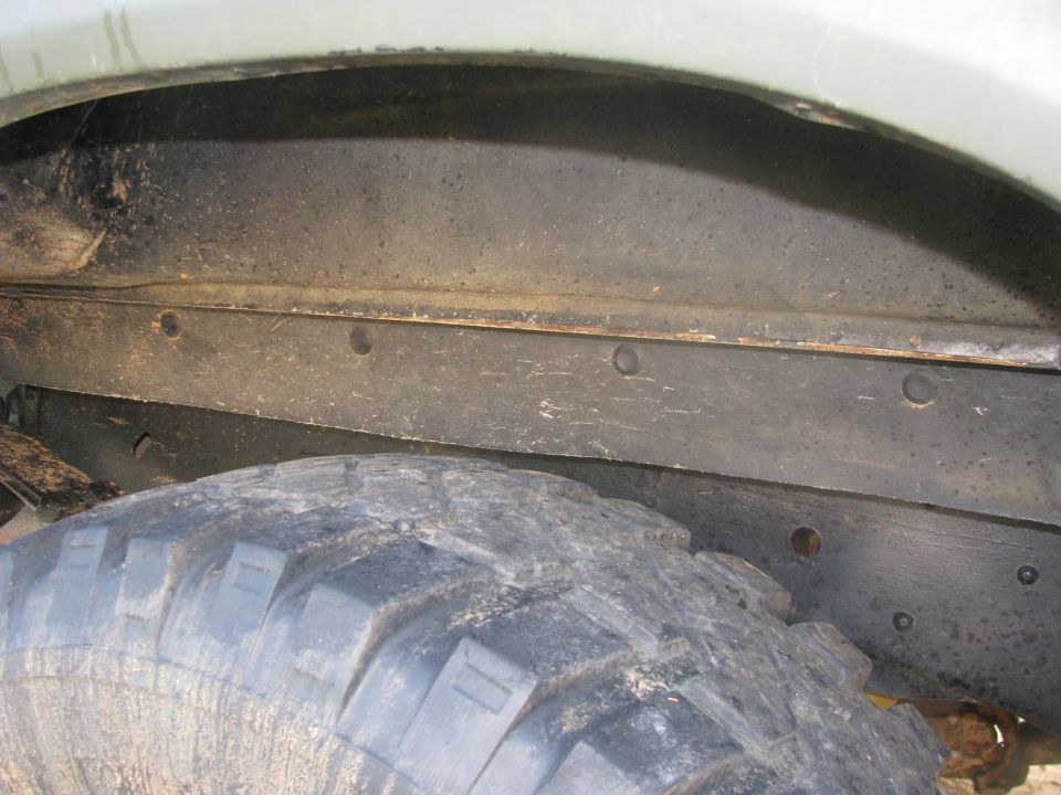 close-up of a dirty tire and the frame inside a vehicle's wheel well
