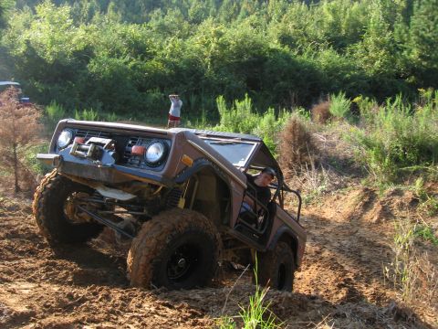 1967 Ford Mustang - Modified Ford Bronco tackling a challenging muddy off-road course.