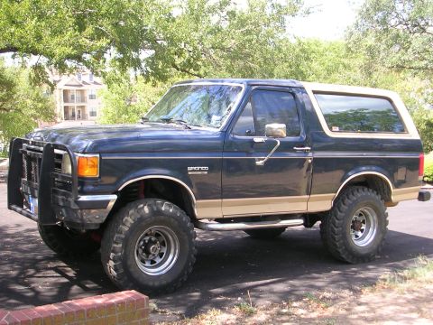 1990 Ford Bronco - This 1990 Ford Bronco features a dark blue body with tan accents and a heavy-duty brush guard on the front.