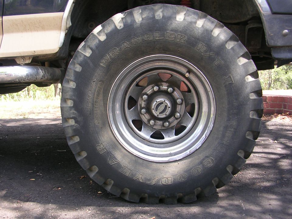 Close-up of a large Goodyear Wrangler M/T tire on a silver wheel with a chrome hubcap