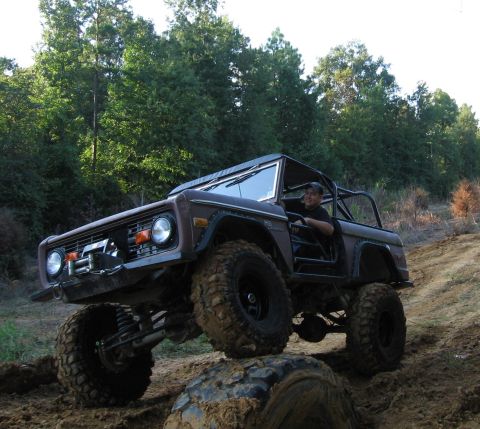 1967 Ford Mustang - A lifted, brown Ford Bronco navigates an off-road trail, demonstrating its off-road capabilities.
