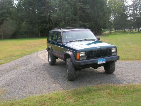 1995 Jeep Cherokee - This 1995 Jeep Cherokee is shown from a 3/4 front view, parked on a gravel driveway with a wooded background.