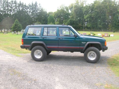 1995 Jeep Cherokee - Side view of a green 1995 Jeep Cherokee with aftermarket wheels and tires.