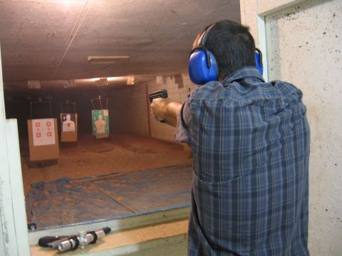 2001 Ford F-150 - A person practices shooting at targets in an indoor range, wearing protective headphones and holding a handgun.