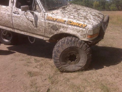 1992 Ford F-350 - This heavily muddied 1992 Ford F-350 pickup truck is viewed from the front three-quarter angle, showing its off-road modifications.