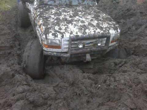 1992 Ford F-350 - This Ford F-350 is deep in the mud, with its tires submerged and body splattered.