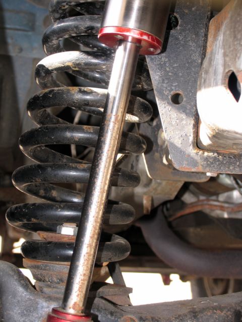 1984 Ford Bronco - Detail of a vehicle's suspension system, showing a shock absorber and coil spring.