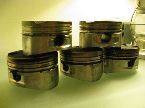 1994 Ford Probe - Several engine pistons are piled together, showing signs of wear and tear.