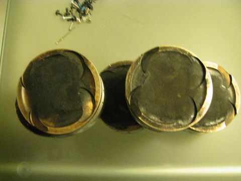 1994 Ford Probe - A set of four pistons, likely from an engine, are displayed on a surface. The registry claims this is a 1994 Ford Probe, but the image show…