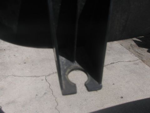 1996 Ford C-350 (Centurion Conversions) - A close-up view of a black metal bracket with a distinctive circular cutout, resting on a cracked concrete surface.