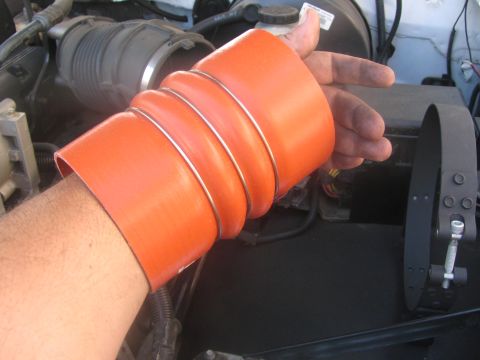 1996 Ford C-350 (Centurion Conversions) - A person is holding an orange silicone hose in the engine compartment of a vehicle.