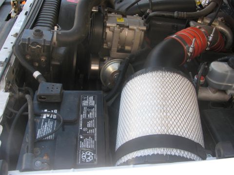 1996 Ford C-350 (Centurion Conversions) - Close-up view of an engine bay, highlighting an aftermarket air intake system and the vehicle's battery.