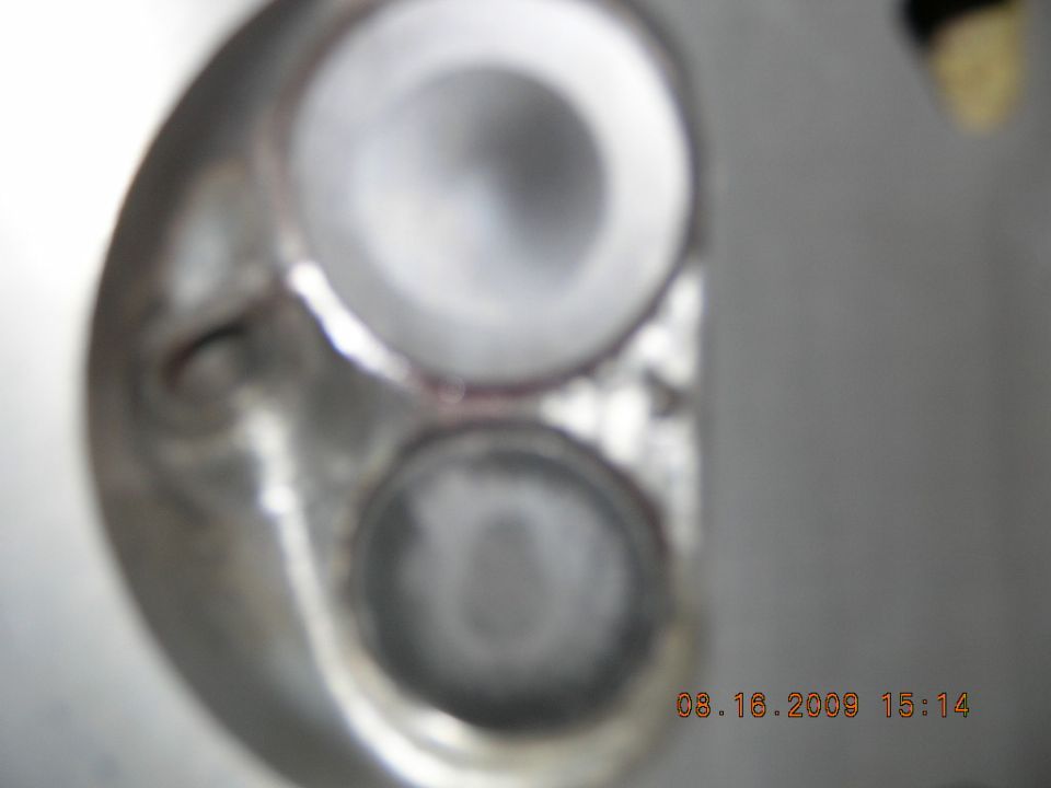 Close-up of a cylinder head showing two valve openings. Watermark reads 08.18.2009 15:14 SUPERMOTORS www.supermotors.net