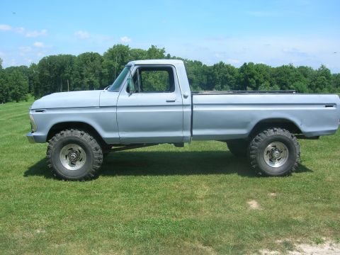 1975 Ford F-250 - Side profile of a lifted 1975 Ford F-250 pickup truck with off-road tires, painted in primer.