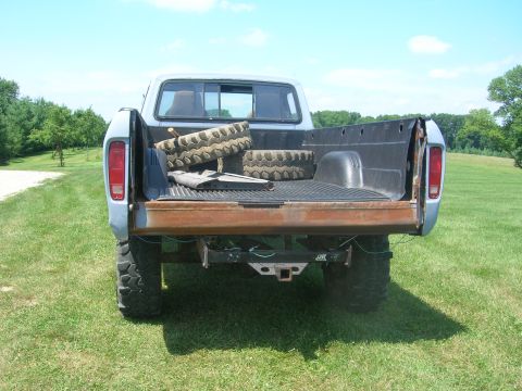 1975 Ford F-250 - This lifted Ford pickup truck has a rusty tailgate and two spare tires loaded in the bed.