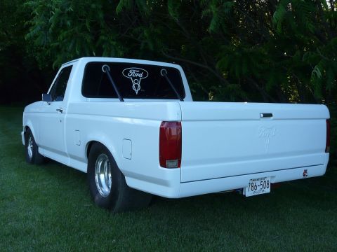1994 Ford F-150 - This white Ford F-150 pickup truck is parked on grass with trees in the background.