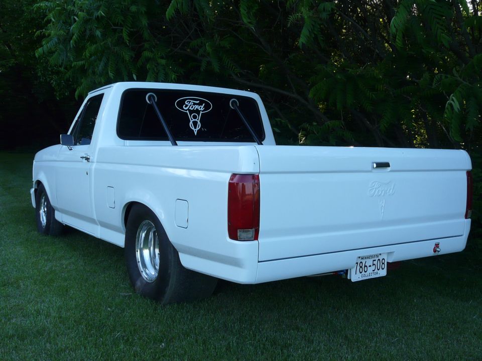 White Ford F-150 pickup truck, rear view. Has a Ford logo sticker on the back window