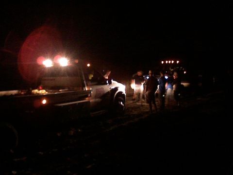 1998 Dodge 1500 - Several vehicles and people are visible at night, illuminated by bright lights.