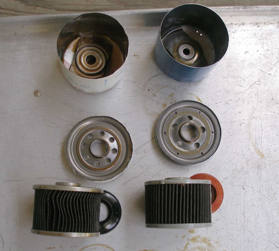 Two oil filters cut apart showing cans, base plates and pleated paper elements laid out