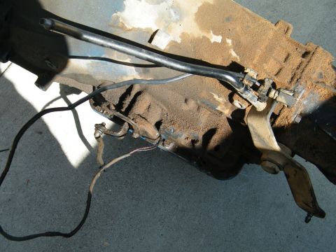 1982 Ford Bronco - Close-up of vehicle transmission linkage and a portion of the transmission casing.