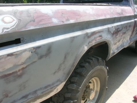 1975 Ford F-250 - Side view of a truck body undergoing repair, revealing primer and body filler.