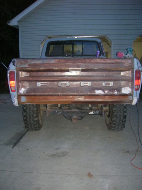 1975 Ford F-250 - The rear of a weathered Ford pickup truck is shown, with the word 'FORD' visible on the tailgate.