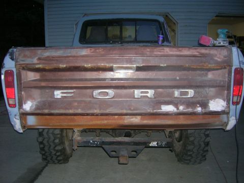 1975 Ford F-250 - Rear view of a weathered Ford pickup truck, showing its tailgate and rear tires.