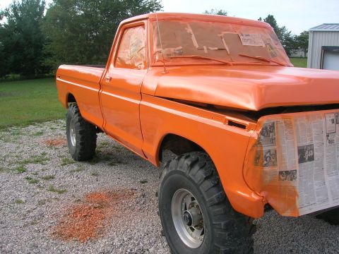 1975 Ford F-250 - This orange pickup truck appears to be undergoing a paint job, with masking tape and newspaper protecting various parts.