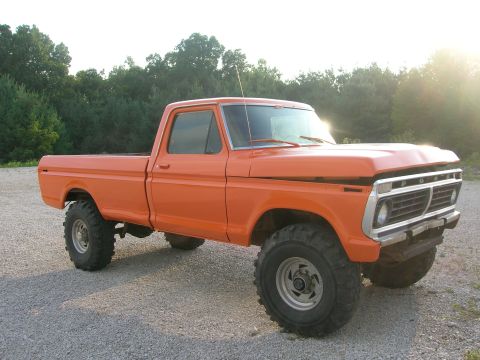 1975 Ford F-250 - This orange 1975 Ford F-250 pickup truck is shown from a 3/4 front angle, highlighting its grille and lifted stance.