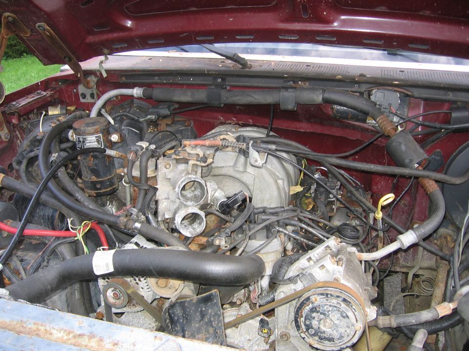 Maroon engine bay with visible engine components, hoses, and wiring. A SuperMotors logo is visible at the bottom right