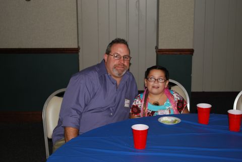1996 Ford Bronco - A man and a girl are seated at a table covered with a blue tablecloth.