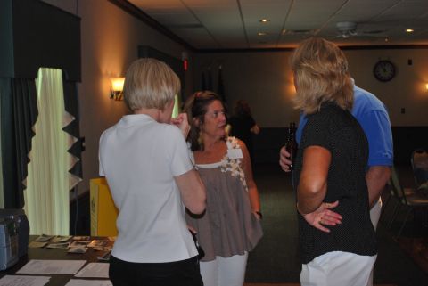 1996 Ford Bronco - Attendees converse during a reunion event, with a clock visible on the wall in the background.