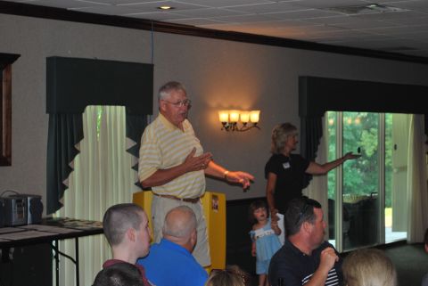 1996 Ford Bronco - A man gestures while speaking to an audience at an indoor event with large windows in the background.