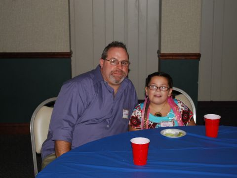 1996 Ford Bronco - A man and a young girl are seated at a table covered with a blue cloth, with red cups and plates visible.