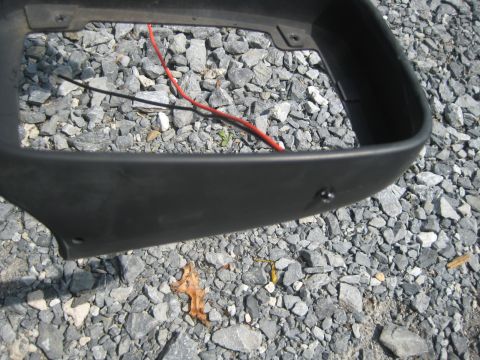 1993 Ford Probe - Close-up of an automotive part with exposed wires, resting on a gravel surface.
