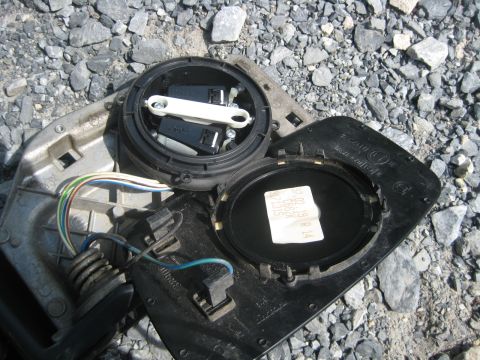 1993 Ford Probe - A disassembled side mirror assembly, showing internal components and wiring, lies on a gravel surface.