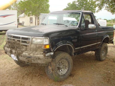 1992 Ford Bronco - This black Ford Bronco is heavily covered in mud, suggesting it has been off-roading.
